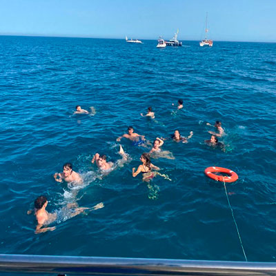 Personas nadando en el mar junto al catamarán