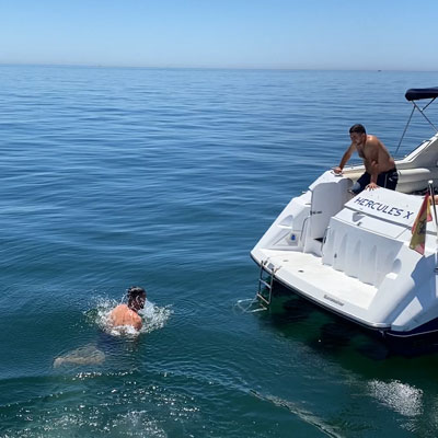 Señor bañándose en el mar junto a un barco